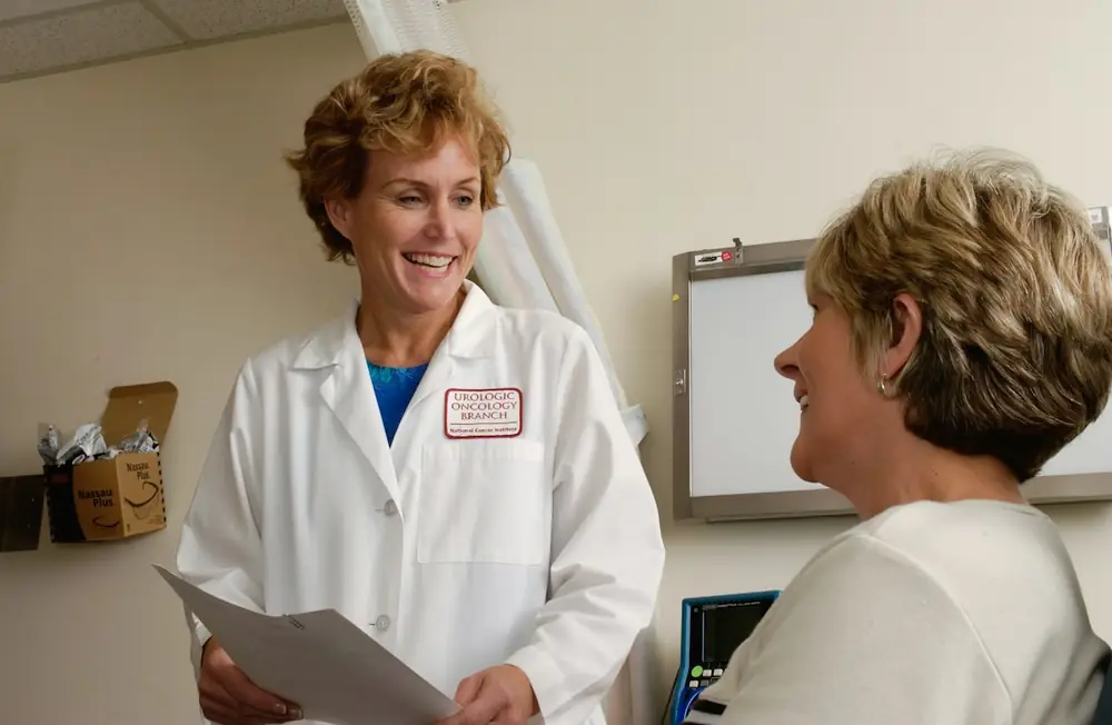 A doctor in a white coat smiling while talking with a patient in a clinic